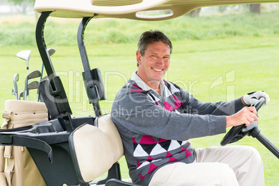 Happy golfer driving his golf buggy smiling at camera