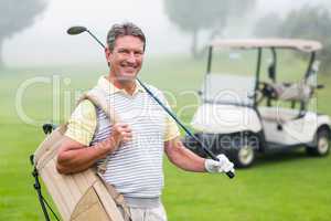 Happy golfer with golf buggy behind