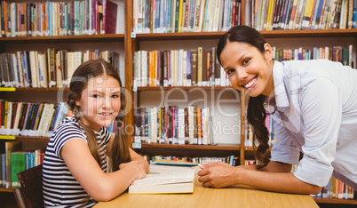 Female teacher and little girl in library