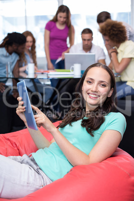 Student using digital tablet with friends in background