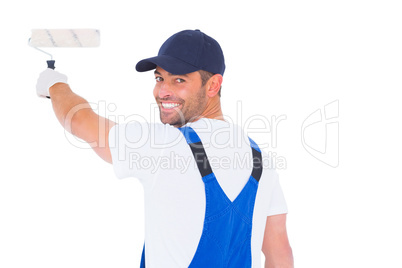 Portrait of handyman in overalls using paint roller