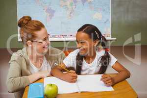 Teacher assisting girl with homework in classroom