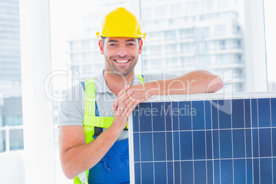 Happy handyman with solar panel in bright office
