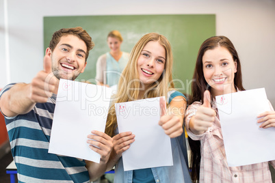 Happy students with papers gesturing thumbs up