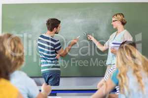 Student and teacher pointing at blackboard