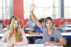Male student raising hand in classroom