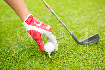 Golfer placing golf ball on tee