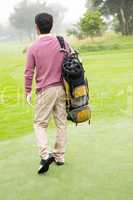 Golfer walking away holding golf bag