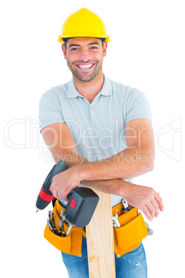 Smiling male carpenter with power drill and plank