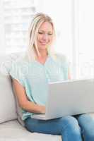 Young woman using laptop while sitting on sofa