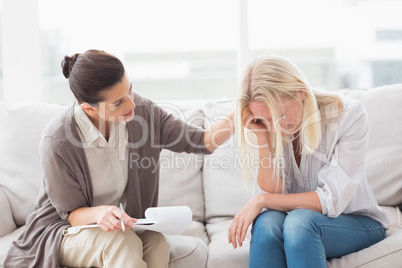 Therapist comforting upset woman on sofa