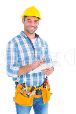 Portrait of smiling handyman writing on clipboard