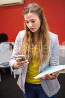 Casual businesswoman text messaging in office
