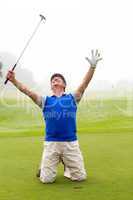 Kneeling golfer cheering on putting green