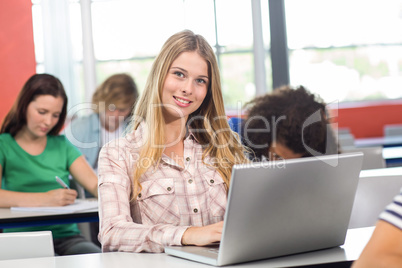 Female student using laptop in classroom