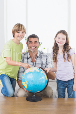 Father with son and daughter exploring map on globe