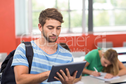 Male student using digital tablet in classroom