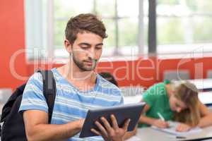 Male student using digital tablet in classroom