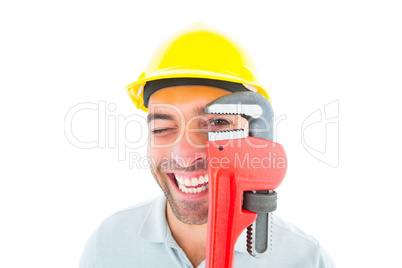 Cheerful handyman looking through monkey wrench