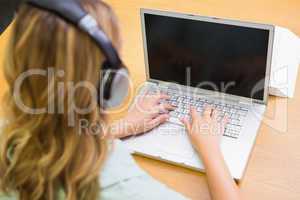 Pretty student studying in the library with laptop