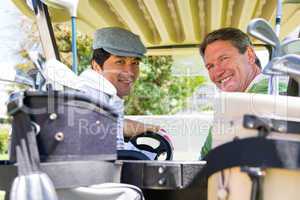 Golfing friends driving in their golf buggy smiling at camera