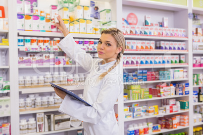 Junior pharmacist taking medicine from shelf