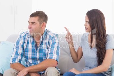 Woman arguing with man while sitting on sofa