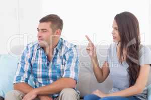 Woman arguing with man while sitting on sofa