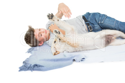 Boy playing with dog while lying on blanket