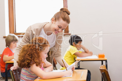 Pretty teacher helping pupil in classroom