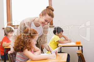 Pretty teacher helping pupil in classroom