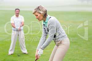 Lady golfer teeing off for the day watched by partner
