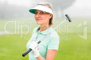 Golfer standing and swinging her club smiling at camera