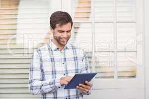 Happy man smiling at camera holding tablet