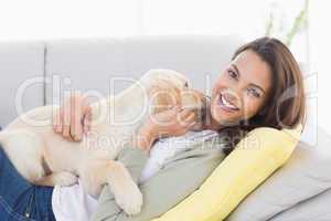 Woman playing with puppy on sofa