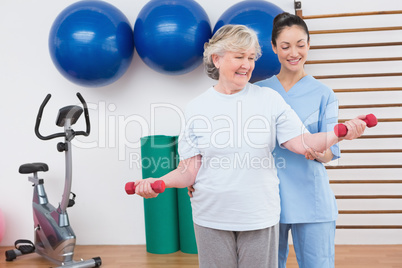 Therapist helping senior woman fit dumbbells