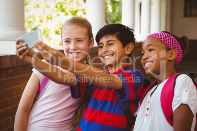 Happy kids taking selfie in school corridor