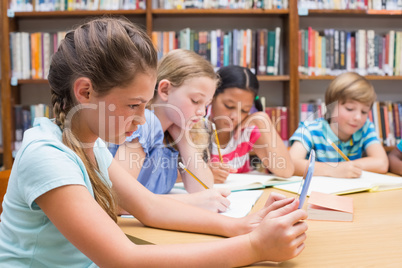 Cute pupil using tablet computer in library