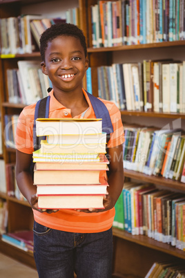 Cute little boy carrying books in library