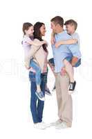 Side view of parents giving piggyback ride to children