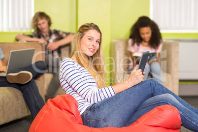 Casual young woman using digital tablet in office