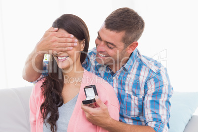 Man covering womans eyes while gifting ring
