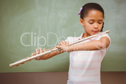 Little girl playing flute in classroom