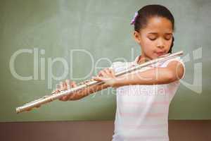 Little girl playing flute in classroom