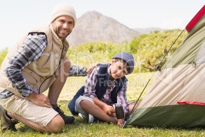 Father and son pitching their tent