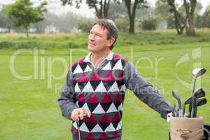 Happy golfer beside his golf bag
