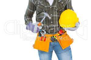 Manual worker wearing tool belt while holding hammer and helmet