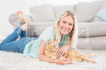 Happy woman with cat lying on rug