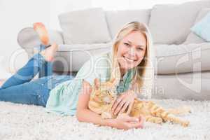 Happy woman with cat lying on rug