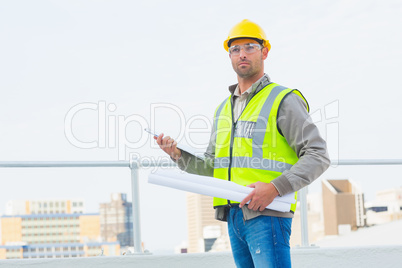 Architect holding blueprints and clipboard outdoors